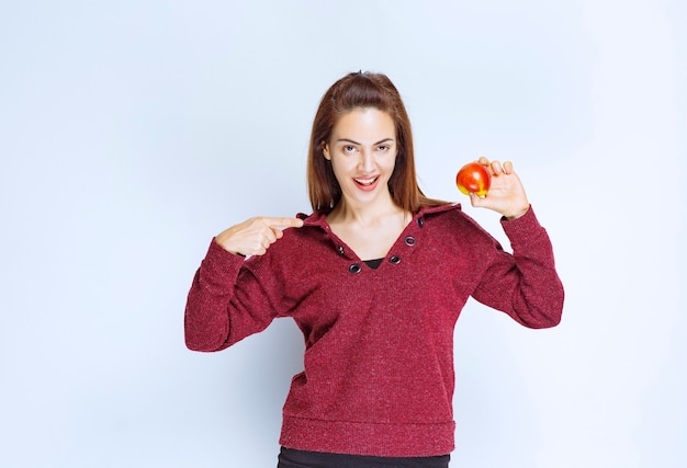 Mujer joven en chaqueta roja sosteniendo una manzana roja