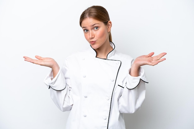 Mujer joven chef aislada de fondo blanco que tiene dudas mientras levanta las manos