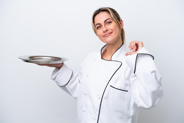 Mujer joven chef con bandeja aislada sobre fondo blanco orgullosa y satisfecha