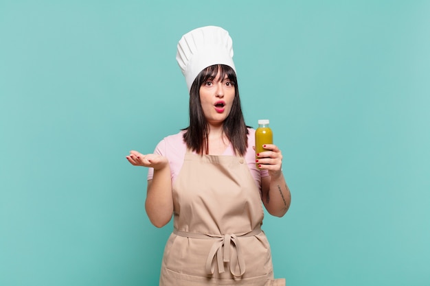 Mujer joven chef con la boca abierta y asombrada, conmocionada y asombrada con una sorpresa increíble