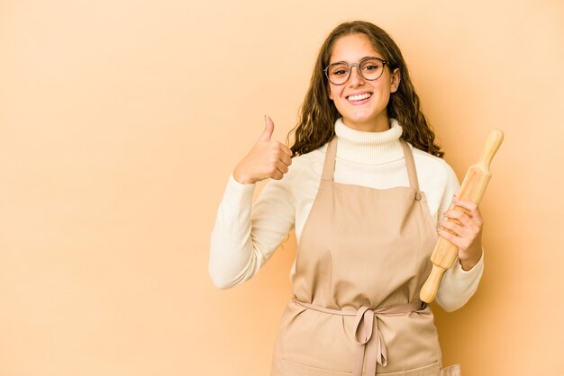 Mujer joven chef caucásico aislado sonriendo y levantando el pulgar hacia arriba