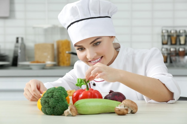 Mujer joven chef con conjunto de verduras en la mesa