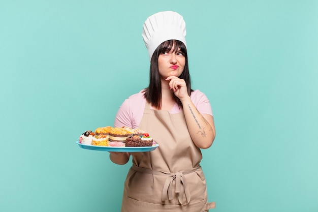 Mujer joven chef pensando, sintiéndose dudoso y confundido, con diferentes opciones, preguntándose qué decisión tomar