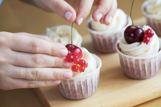 Mujer joven chef de repostería decora cupcakes