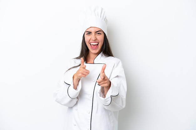 Mujer joven chef sobre fondo blanco apuntando al frente y sonriendo