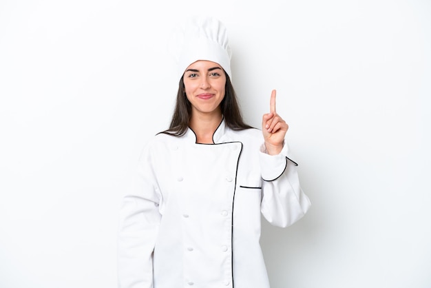 Mujer joven chef sobre fondo blanco señalando con el dedo índice una gran idea