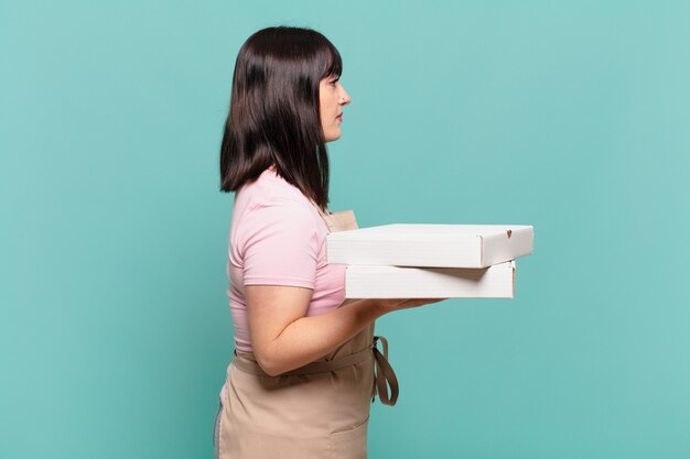 Mujer joven chef en vista de perfil mirando para copiar el espacio por delante, pensando, imaginando o soñando despierto