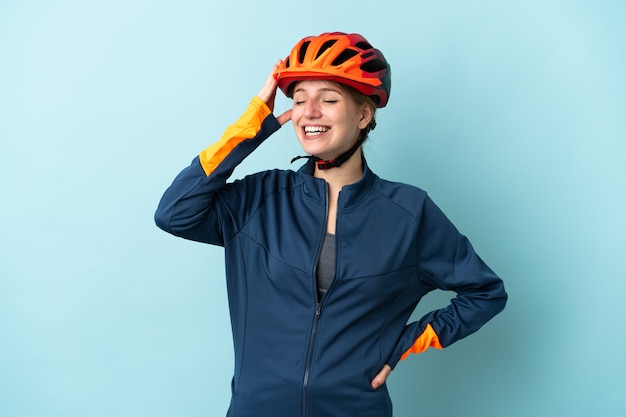 Mujer joven ciclista aislada en azul sonriendo mucho