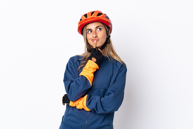 Mujer joven ciclista hispana aislada en blanco con dudas mientras mira hacia arriba