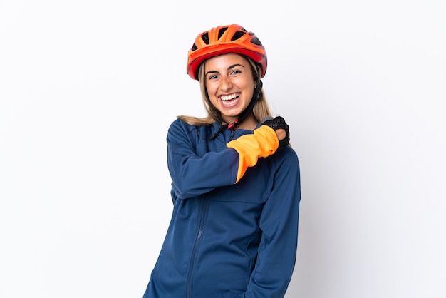 Mujer joven ciclista hispana aislada en la pared blanca celebrando una victoria