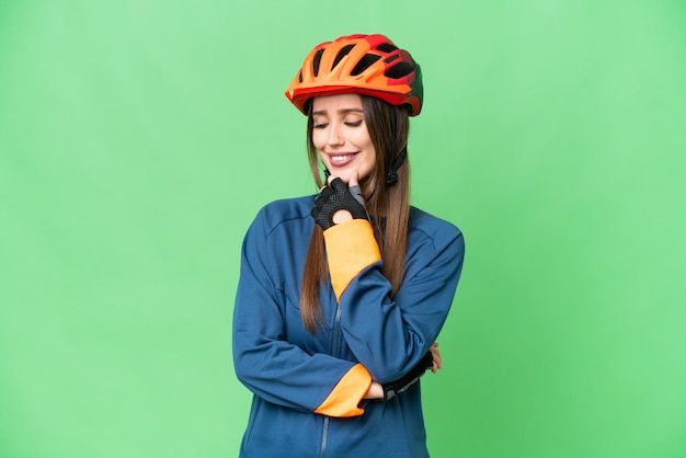 Mujer joven ciclista sobre fondo clave de croma aislado mirando hacia el lado