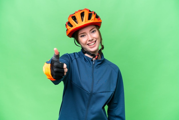 Foto mujer joven ciclista sobre fondo de clave de croma aislado con los pulgares hacia arriba porque algo bueno ha sucedido