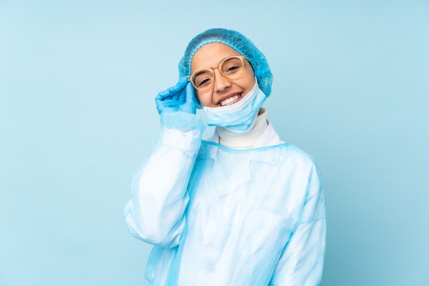 Mujer joven cirujano en uniforme azul con gafas y feliz