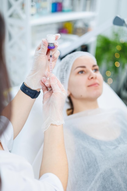 Una mujer joven en una cita con una esteticista inyecciones de belleza para el procedimiento de tratamiento facial en un dermatólogo