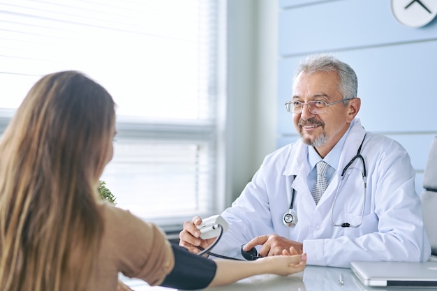 Mujer joven en la cita con el médico. El médico mide la presión del paciente.