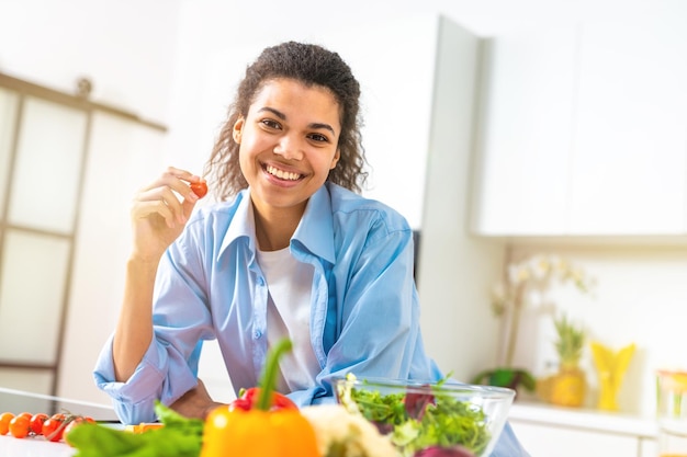 Foto mujer joven en la cocina casera prepara una ensalada genuina con verduras frescas