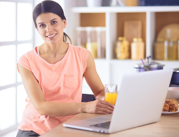 mujer joven, en, cocina, con, computadora de computadora portátil, mirar, recetas, sonriente, comida, blogger, concepto