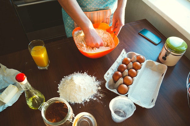 Mujer joven cocinando en la cocina, prepara la masa para hornear