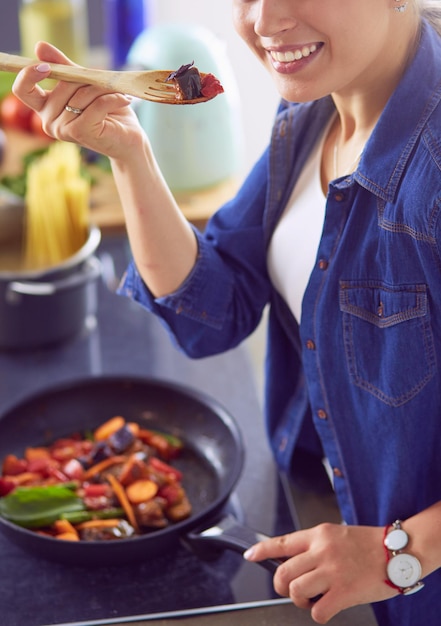 Mujer joven cocinando comida saludable sosteniendo una sartén con verduras es un concepto de estilo de vida saludable cocinando en casa