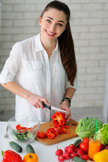 Foto mujer joven cocinando ensalada de verduras saludables