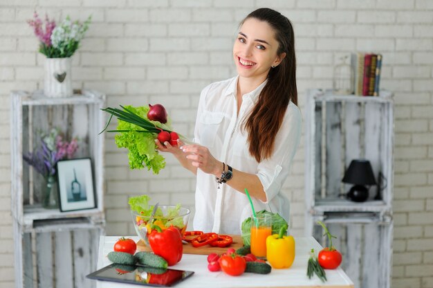 Mujer joven cocinando ensalada de verduras saludables