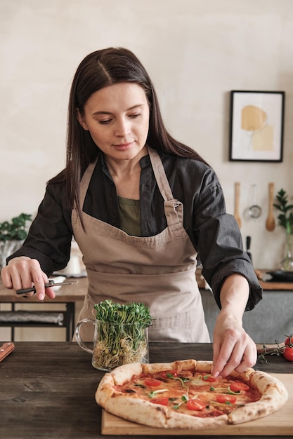 Mujer joven cocinando pizza casera