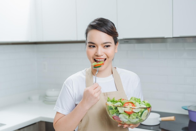 mujer joven, comida, ensalada mezclada, en, cocina