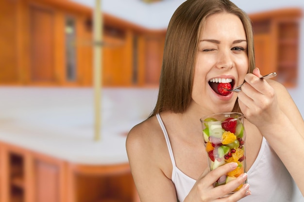 Foto mujer joven, comida, frutas, de, vidrio, en, habitación, plano de fondo