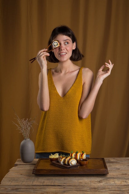 Mujer joven comiendo y disfrutando de rollo de sushi fresco con palillos