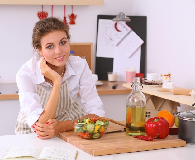 Mujer joven comiendo ensalada fresca en la cocina moderna