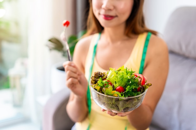 Mujer joven comiendo ensalada saludable casera en casa