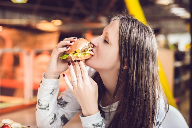 Mujer joven comiendo hamburguesa mujer comiendo comida chatarra, hamburguesa de comida grasosa