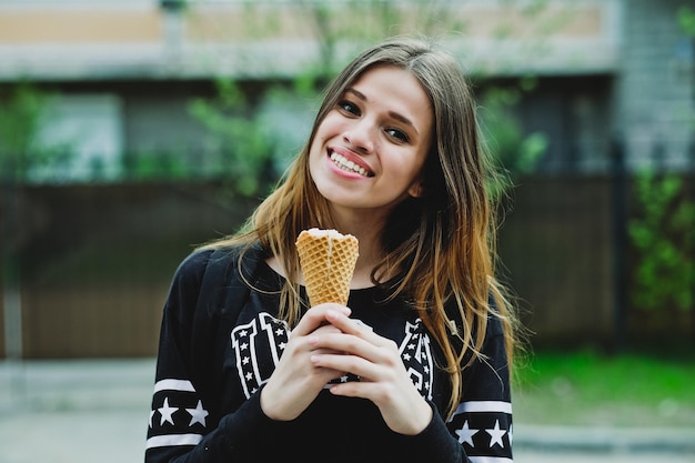Mujer joven comiendo helado día soleado al aire libre, cerca de la casa grande