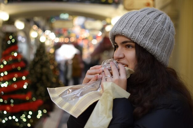 Mujer joven comiendo un mercado navideño compró espacio de copia de rollo de canela