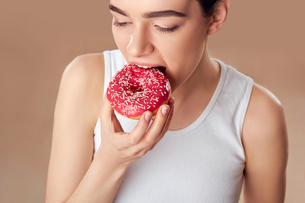 Mujer joven comiendo postre glaseado con chispitas.