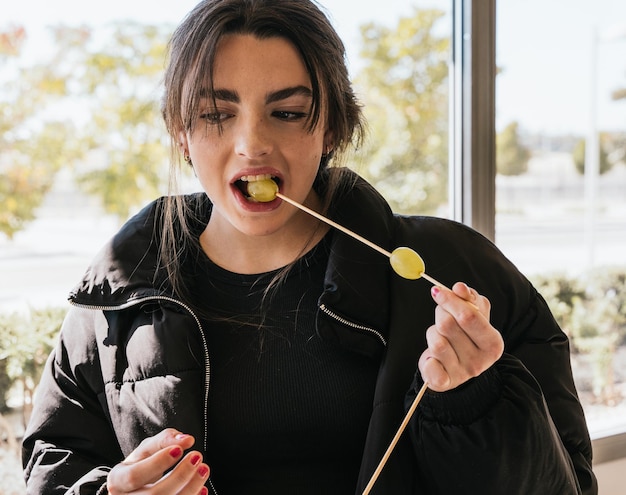 Foto mujer joven comiendo uvas durante el día