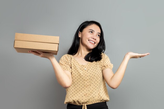 Mujer joven comparando caja de cartón en la palma con una mano vacía