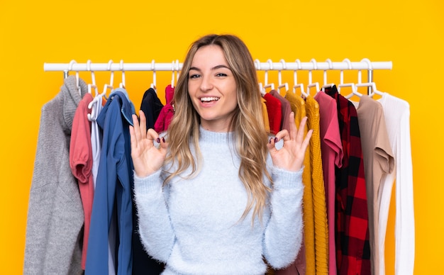 Mujer joven comprando algo de ropa sobre pared aislada