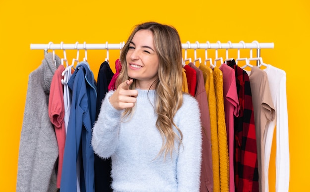 Foto mujer joven comprando algo de ropa sobre pared aislada