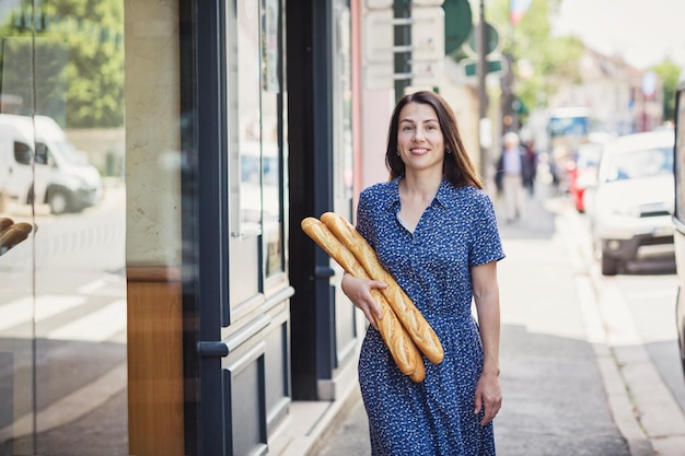 Mujer joven comprando una baguette francesa