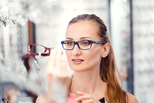 Mujer joven comprando gafas en la tienda