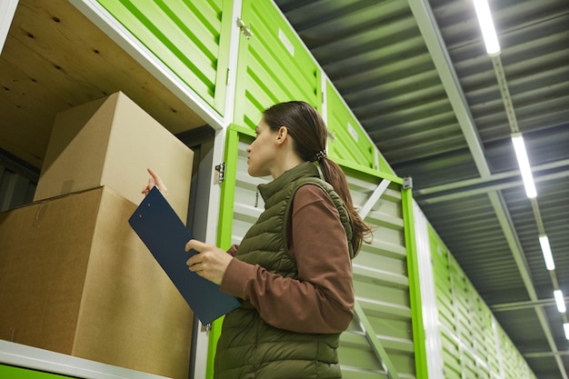 Foto mujer joven comprobando las cajas y empaquetando en almacenamiento