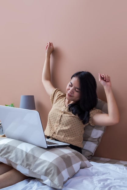 mujer joven, con, computador portatil, en cama, mientras, extensión, manos