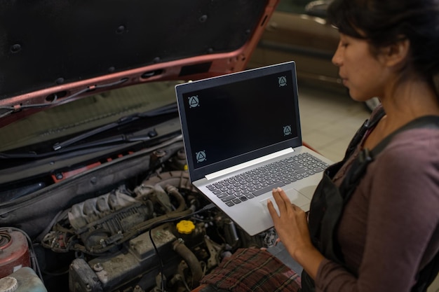 mujer joven, con, computador portatil, posición, delante de, capó abierto, de, coche