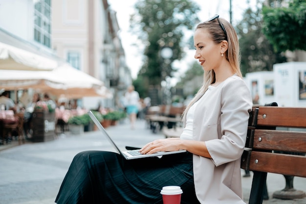 mujer joven, con, un, computador portatil, sentado, en, un, banco