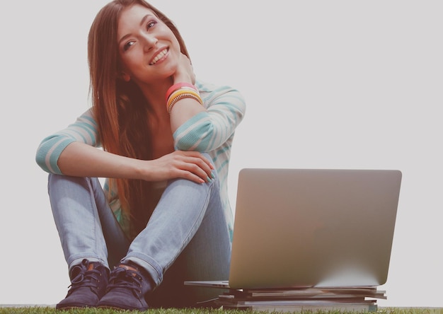 mujer joven, con, computador portatil, sentado, en, pasto verde, portreit, mujer joven