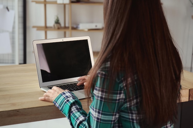 Mujer joven con la computadora portátil en casa