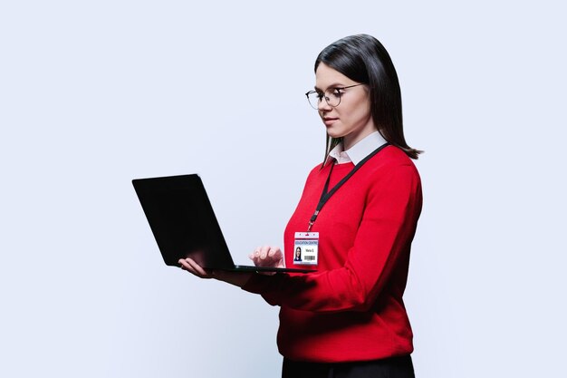 Foto mujer joven con una computadora portátil con la insignia del centro educativo en fondo blanco