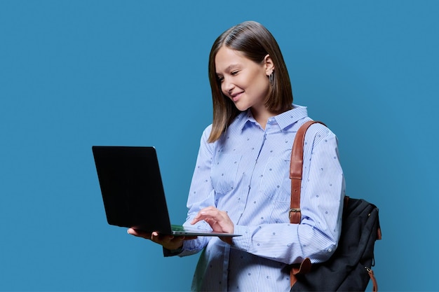 Mujer joven con una computadora portátil en las manos sobre un fondo azul