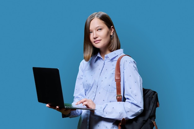 Mujer joven con una computadora portátil en las manos sobre un fondo azul